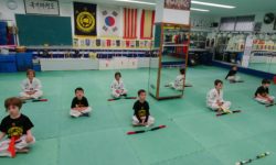 Nens practicant un exercici de relaxació durant una classe de Taekwondo infantil a l'Escola Chois Lee de Girona.