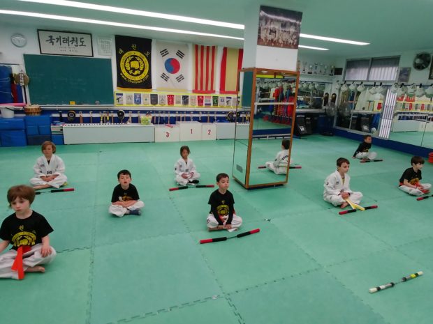Nens practicant un exercici de relaxació durant una classe de Taekwondo infantil a l'Escola Chois Lee de Girona.